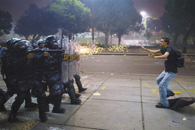 6月20日，巴西里约热内卢，一名示威者面对一排防暴警察。观察人士称，动荡局势打击了巴西，因为该国正在举办联合会杯赛事。