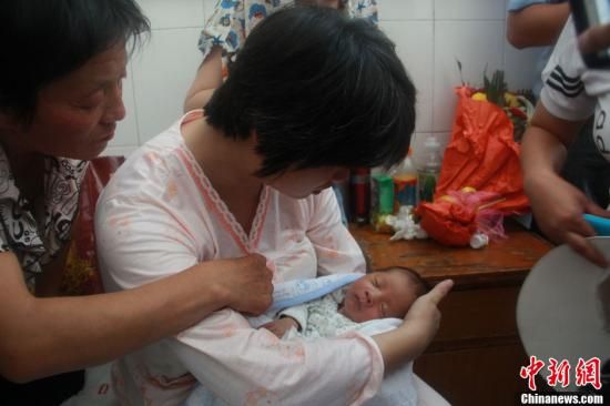 图为陕西富平“产科医生拐卖婴儿”一案中的被拐婴儿于8月5日中午在该县妇幼保健院由当地警方交于其父母。张一辰 摄