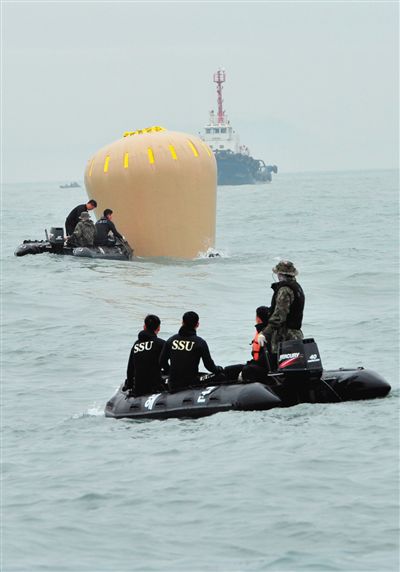 18日，搜救人员准备将气囊捆绑到沉没客轮上。