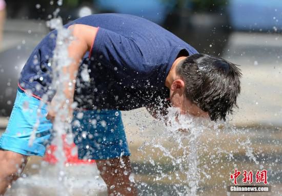 5月29日，一名小孩将头伸向北京街头的喷泉以降温祛暑。