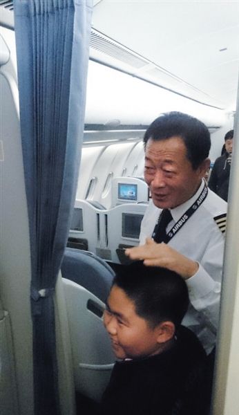 11月10日晚，飞机备降后，机长贺中平微笑着摸着一位男孩的头。网友供图