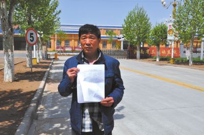 刘建国拿着检测报告在河南省三门峡监狱门口。