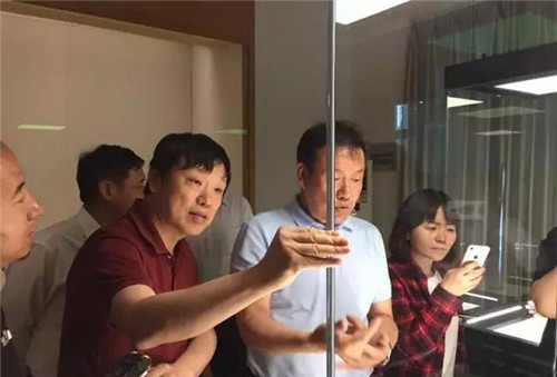 胡锡进主编在马总介绍文物存放柜的玻璃时，用手捏了捏感受下玻璃的存在。