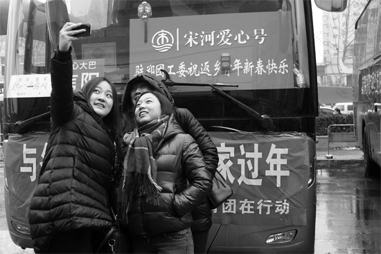昨天上午8时，郑州正道中环百货广场，准备回家的老乡在爱心大巴车前合影留念