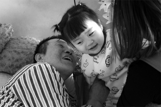 病床前李刚父女俩说着“悄悄话”，幸福的气氛洋溢在病房中