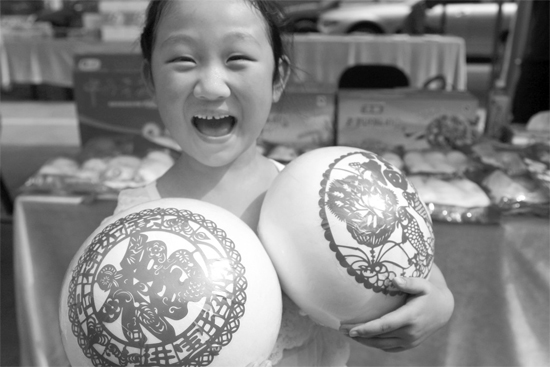 在2013河南食品安全宣传周活动现场，一个小女孩抱着参展的特色大馒头乐开了花