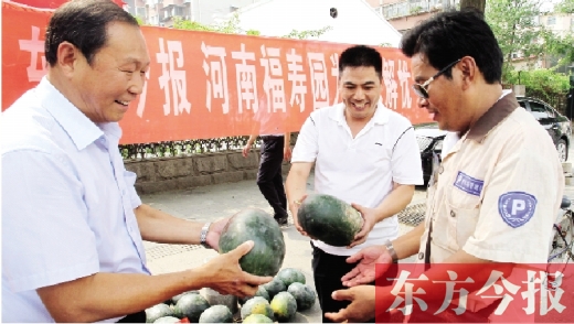 河南福寿园区域总经理吴正宗（左一）、东方今报发行中心副总监王路喜（中）在街头给市民送瓜