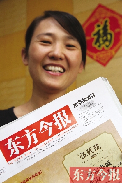 幸运的读者拿着中奖的报纸开心得合不拢嘴