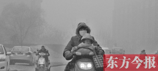 12月8日，郑州市未来路上，一位市民带着孩子在雾中骑行