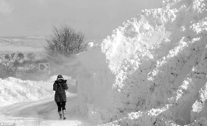 　　北爱尔兰安特里姆峡谷,一名女子在被大雪覆盖的马路上艰难行走。