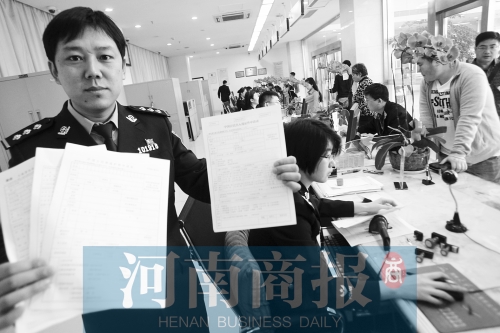 　民警左手拿的是新申请表，右手拿的是三份老申请表 王春胜/摄