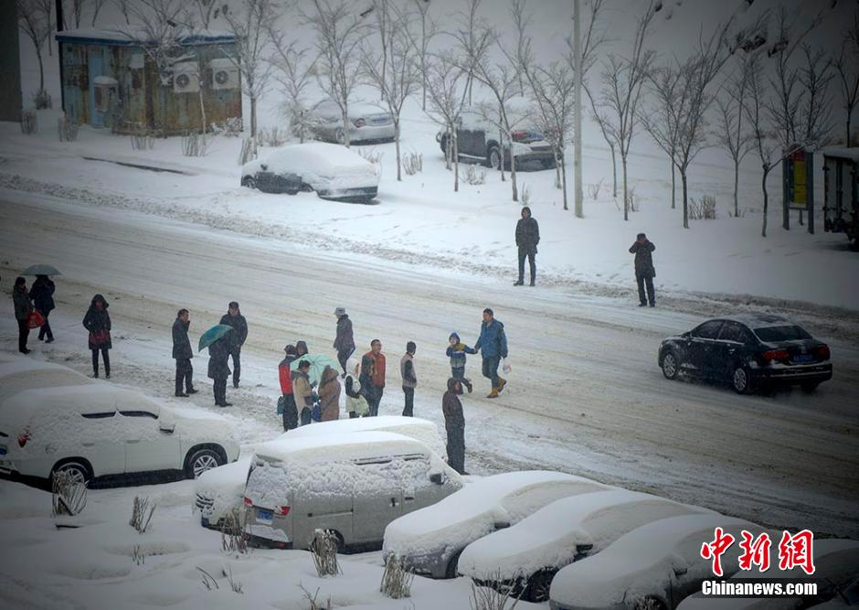 市民在路边等公交车，由于降雪天气很多市民放弃开车