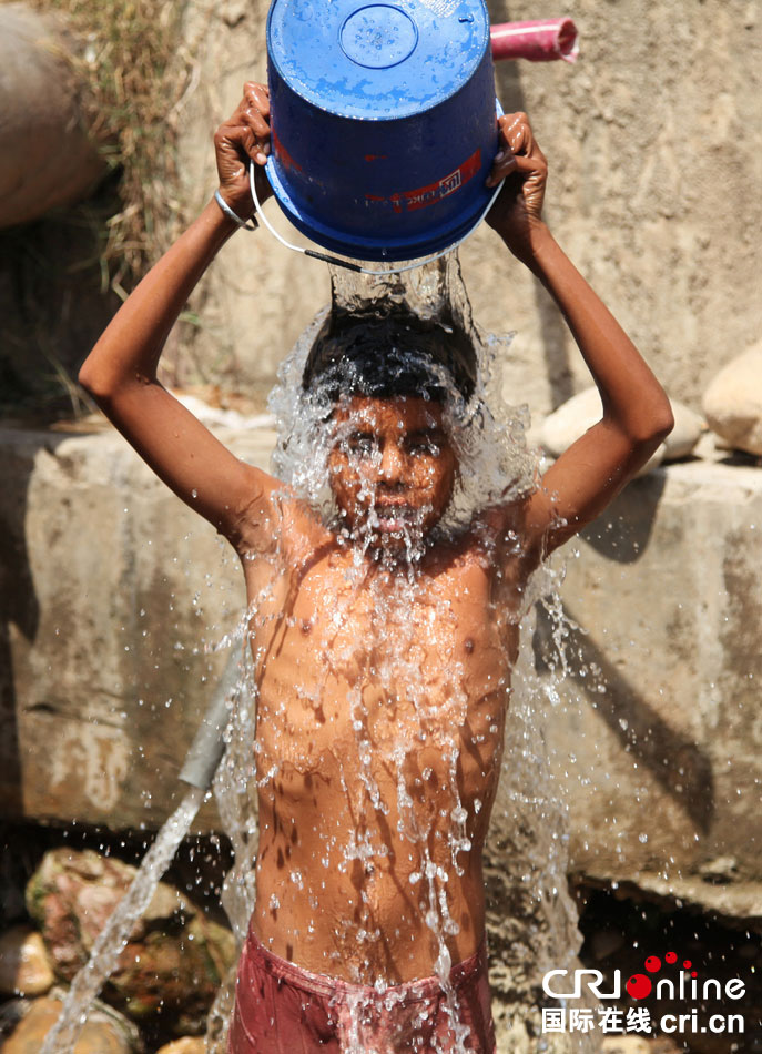 印度查谟，男孩将水浇在脸上。　