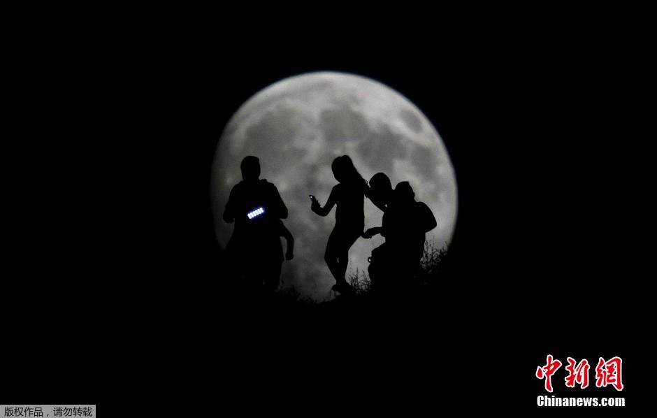 墨西哥蒂华纳，一队远足旅行者的身影映衬在巨大的月亮中，宛如童话场景。