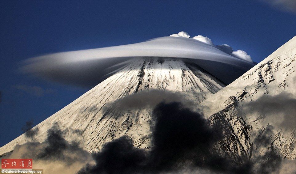 火山上笼罩着类似于外星飞碟形状的云彩，场景犹如科幻大片。