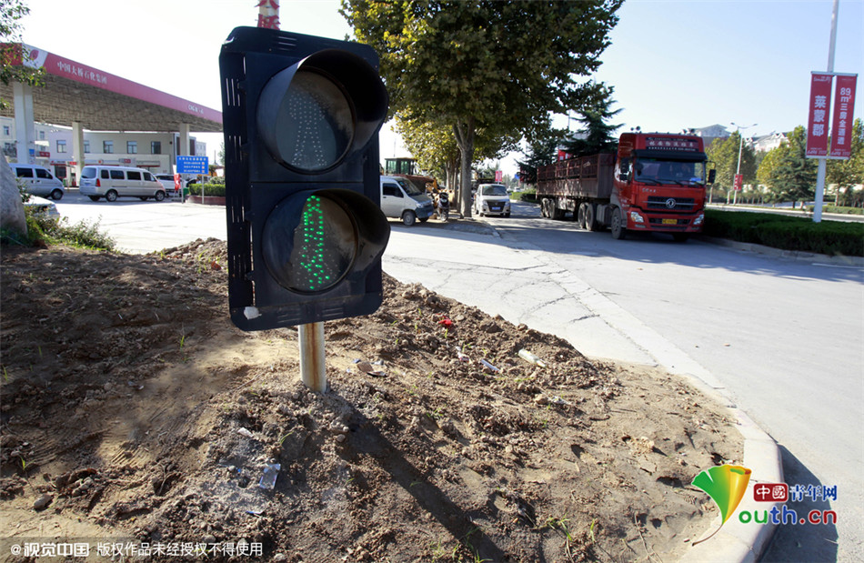 10月27日，郑州中原西路与新田大道交叉口西南角，一只交通信号灯在路边只露出个“脑袋”。
