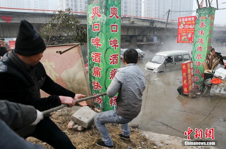 西安市沣东新城西宝高速快速干道高架桥下，枫桥名邸小区附近，众人用绳子将被淹的轿车从水中拉上来。