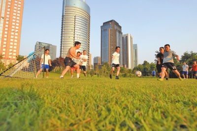 市民在郑州东区城市之林绿地踢球健身