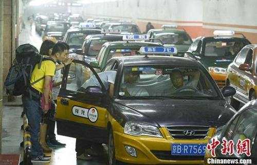 市民在北京西客站出租车候车点准备乘车。中新社发 侯宇 摄