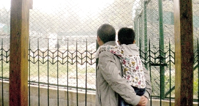 郑州动物园，一名家长背着孩子在熊区前观看