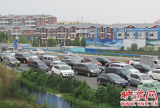记者看到郑州机场收费站口车辆排队，与此形成鲜明对比的是，路的对面（另一半幅）却车辆较少，通行顺畅。