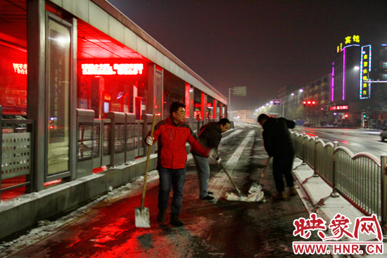 郑州快速公交公司工作人员在农业路天明路BRT站台进站口地面结冰路段抛洒融雪剂