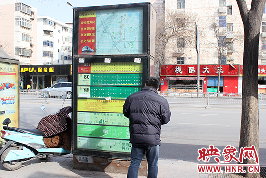 一名男子在贴满小广告的公交站牌前驻足