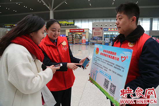 志愿者为旅客讲解“网络文明志愿”的行动内容。