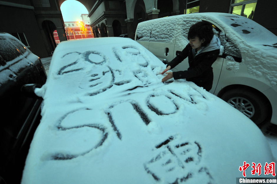 11月18日，行人在车辆的积雪上涂鸦。