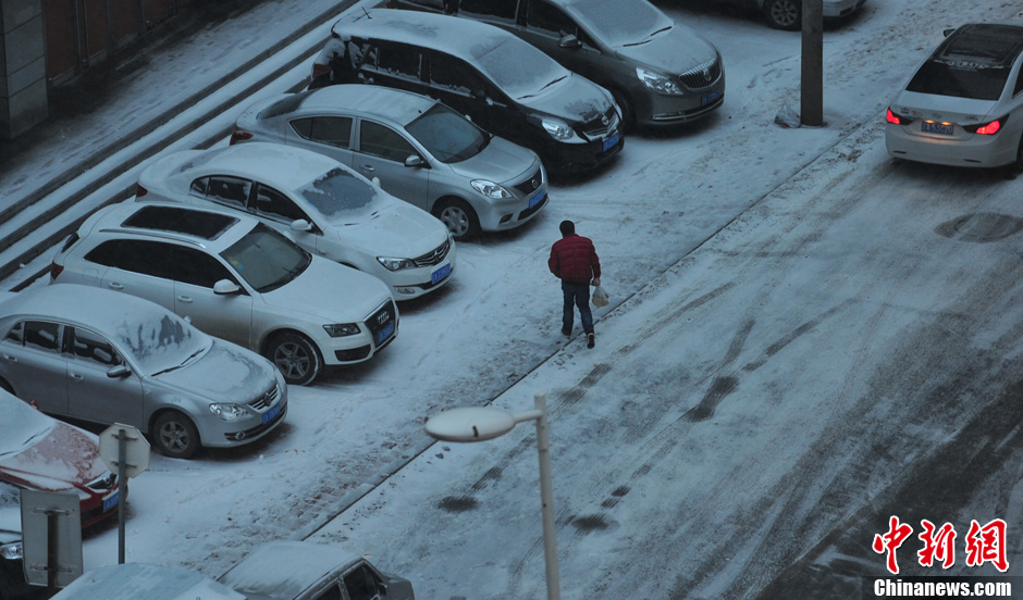 11月18日，行人在沈阳街头的积雪中穿行。