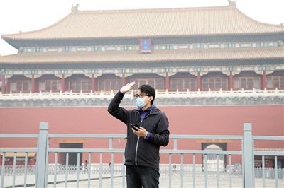 11月1日，北京大部分地区重度污染，一名游客戴着口罩在午门前挥手跟朋友打招呼。 实习生 王飞 摄