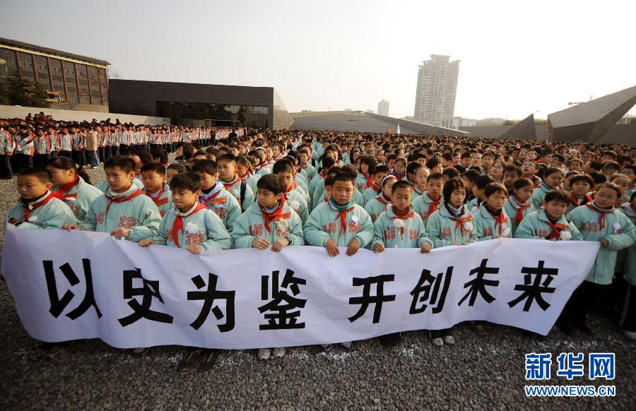，南京市小学生代表手持“以史为鉴 开创未来”的横幅在南京大屠杀遇难同胞纪念馆集会广场参加悼念仪式。　