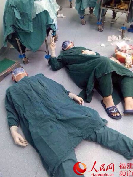 32个小时连续手术后，陈靖和陈松两人累瘫在手术台边，陈松双手给出了胜利的手势