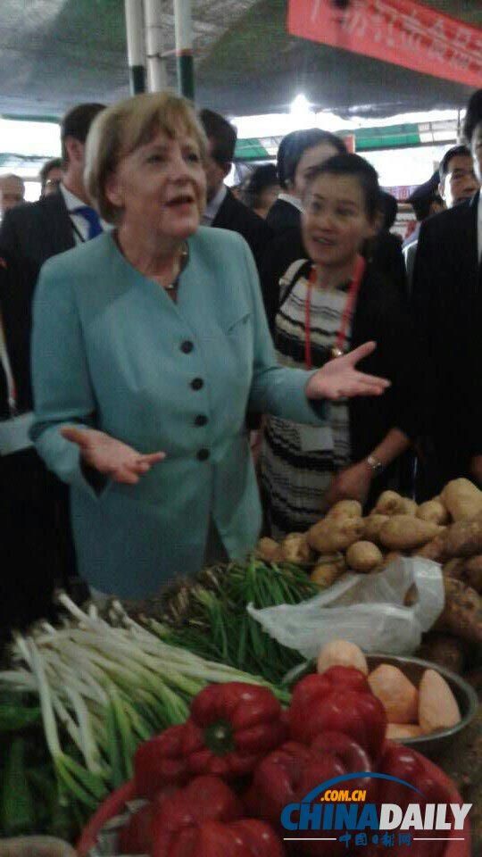 7月6日上午, 德国总理默克尔来到成都一处菜市场参观,在蔬菜区一摊位前驻足。