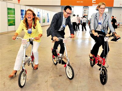 　9日，三名与会人员在会场内试骑磁动车（一种新能源电动车）。今年的夏季达沃斯论坛提出“绿色”理念。