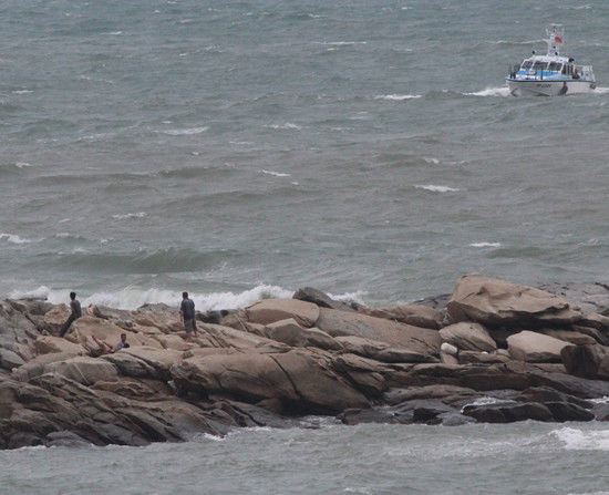 一艘大陆船遭强劲风浪吹袭，搁浅礁岩后在金门水域翻覆，船员分别爬上礁岩，台湾金门县海巡队赶往抢救。