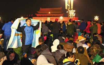 10月1日凌晨，天安门广场，人们穿着厚衣服等候观看升国旗仪式。