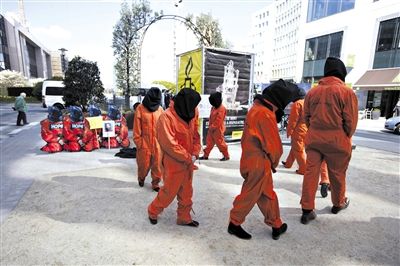 3月25日，比利时布鲁塞尔，人权组织成员打扮成关塔那摩美军监狱囚犯的模样，抗议奥巴马访问比利时。