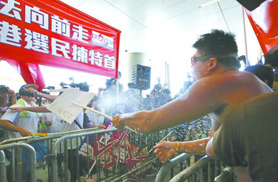 17日，在香港立法会外，一名反对政改的男子向支持派人群投掷标牌。