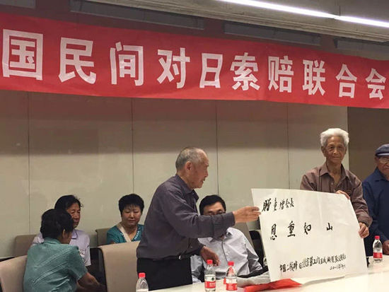 劳工代表之一闫玉成和劳工联谊会副会长赵宗仁（右）拿着“恩重如山”墨宝。