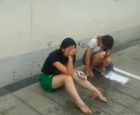 女子坐在地上，用手擦眼睛，表情痛苦。 来源：中国青年网