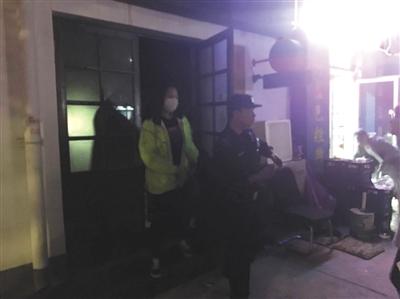昨晚，在宋冬野经营的“NOTHERE不在”酒吧，警方带走一名戴口罩的长发女子及酒吧工作人员。 新京报记者 林斐然 摄