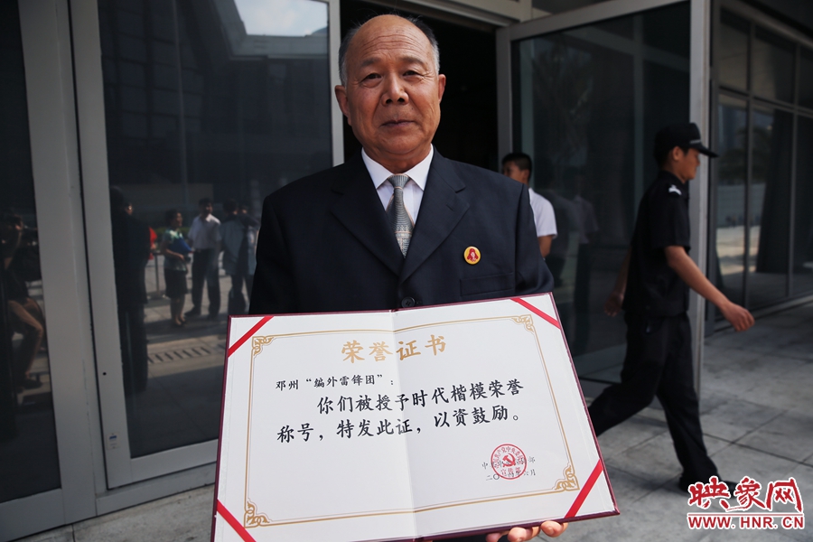 河南邓州“编外雷锋团”团长宋清梅向众多记者展示中宣部授予的“时代楷模”荣誉证书。
