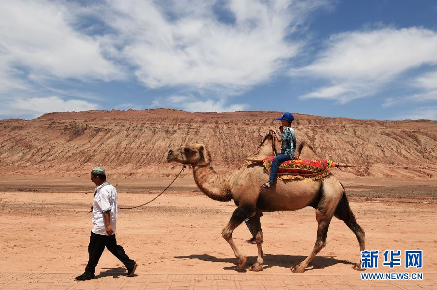 7月13日，一名儿童在新疆吐鲁番火焰山景区骑骆驼游览。