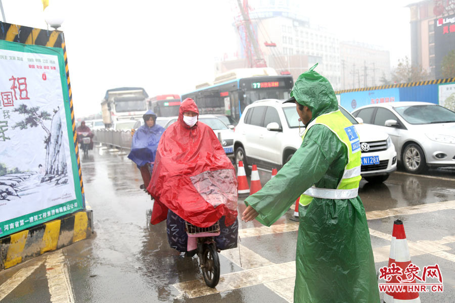 交通协管员下雨天坚守岗位，疏导交通。
