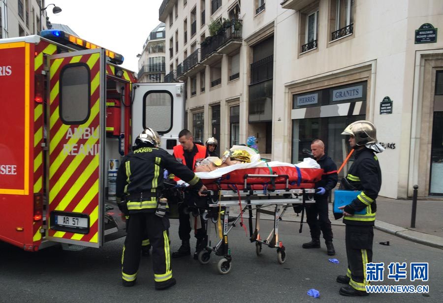  1月7日，在法国巴黎，消防人员在《沙尔利周刊》总部前搬运伤者。