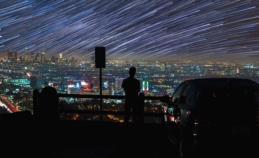 照片中，一名男子看着流星和陨星划过天空。（网页截图）