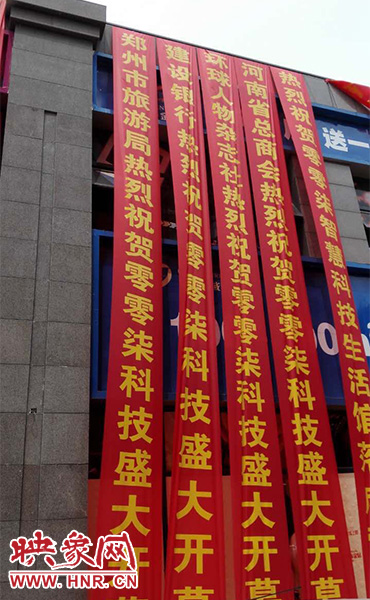 路边一栋楼上悬挂着二三十条红色条幅，全部是祝贺一家公司开业的。