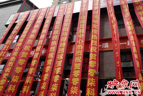 路边一栋楼上悬挂着二三十条红色条幅，全部是祝贺一家公司开业的。