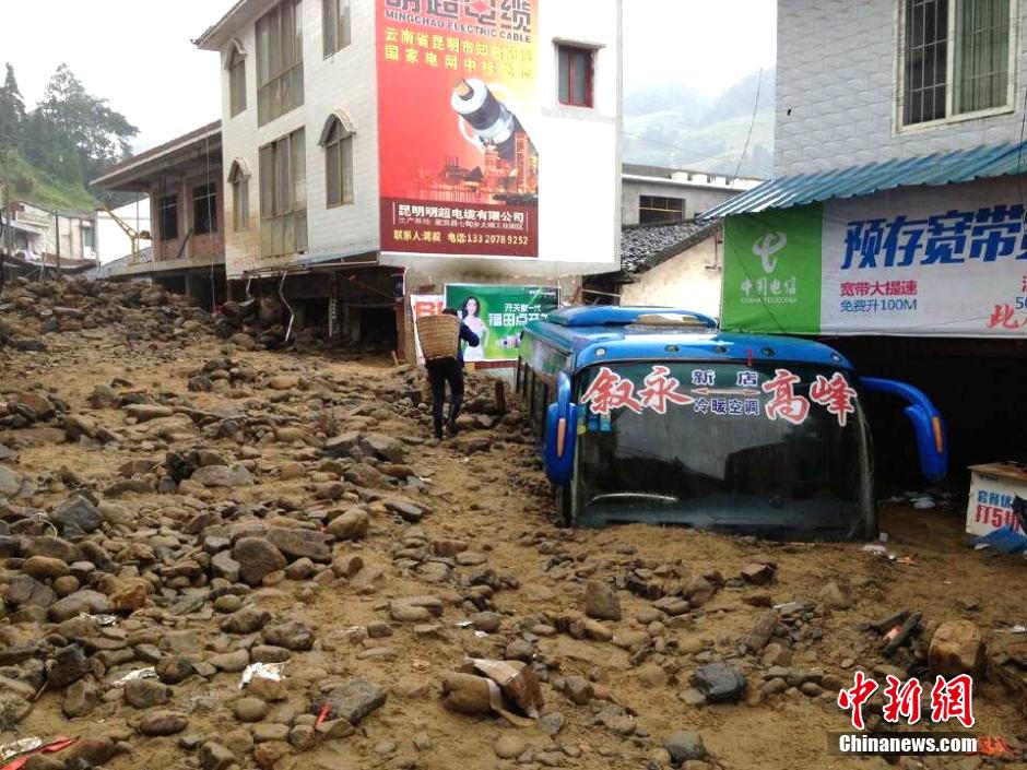图为山洪泥石流导冲进乡镇街道，导致客车被埋。
